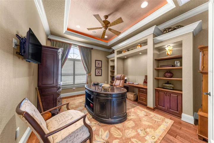 Elegant private office with double-door entry, custom shelving, built-in workspace, and decorative ceiling lighting.