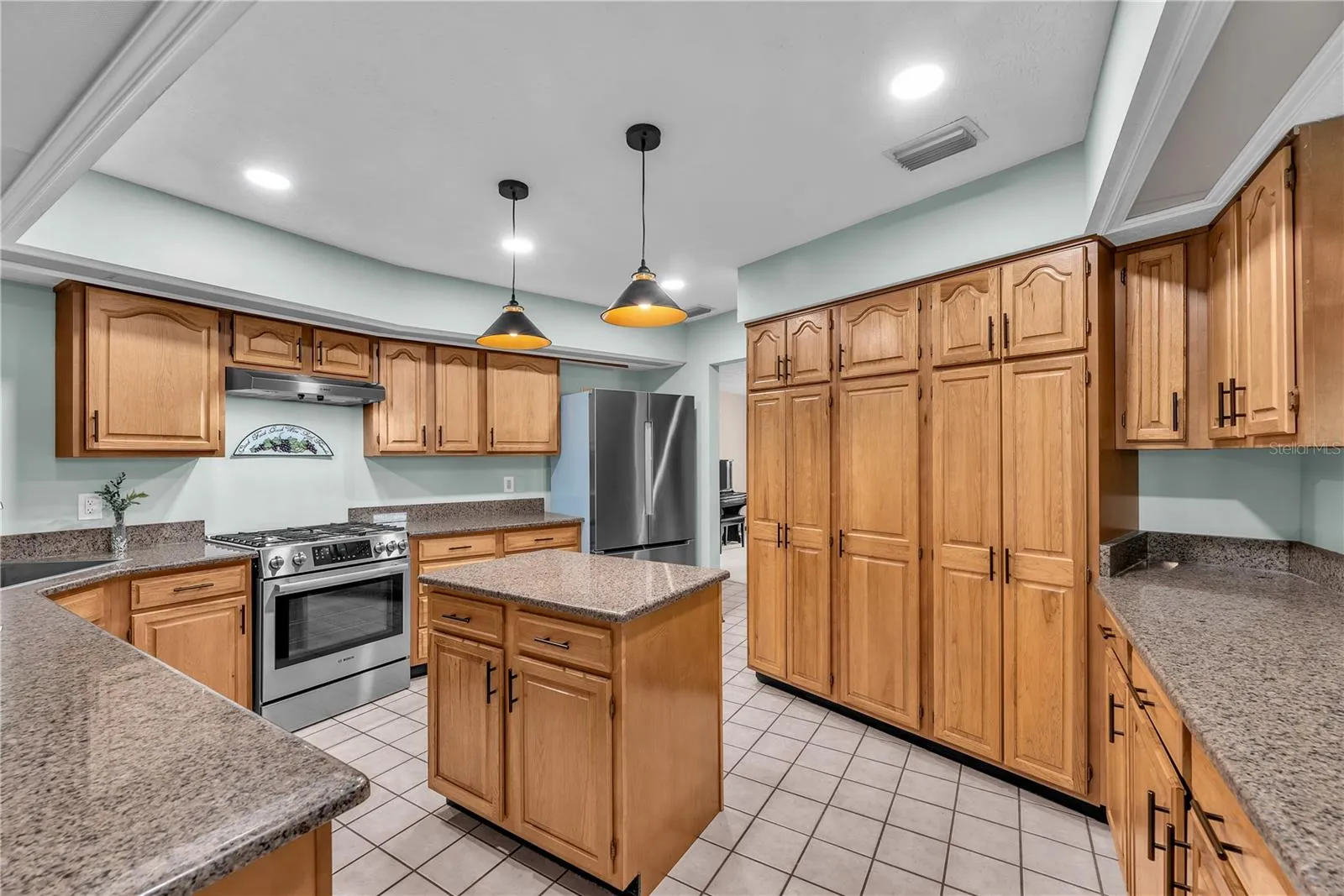 The beautifully appointed kitchen features rich wood cabinetry, gorgeous dark granite countertops, a large cabinet pantry for storage and updated lighting.