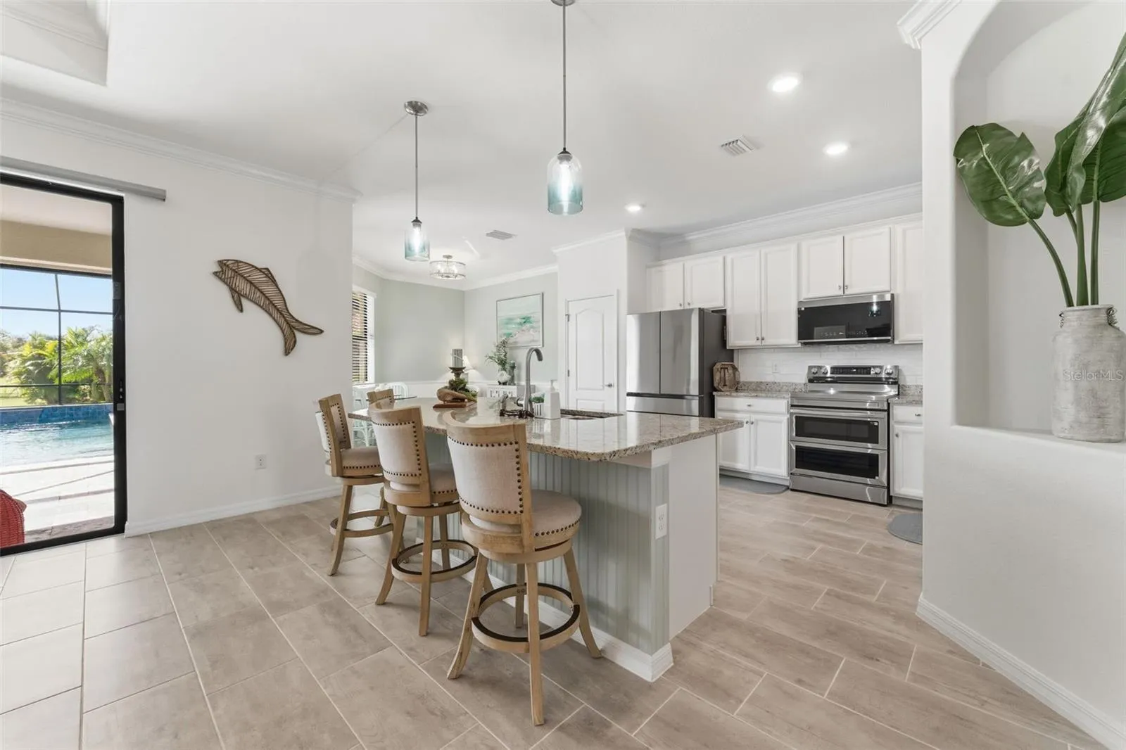 Inviting white kitchen with newer stainless steel appliances and spacious island for casual dining and entertaining