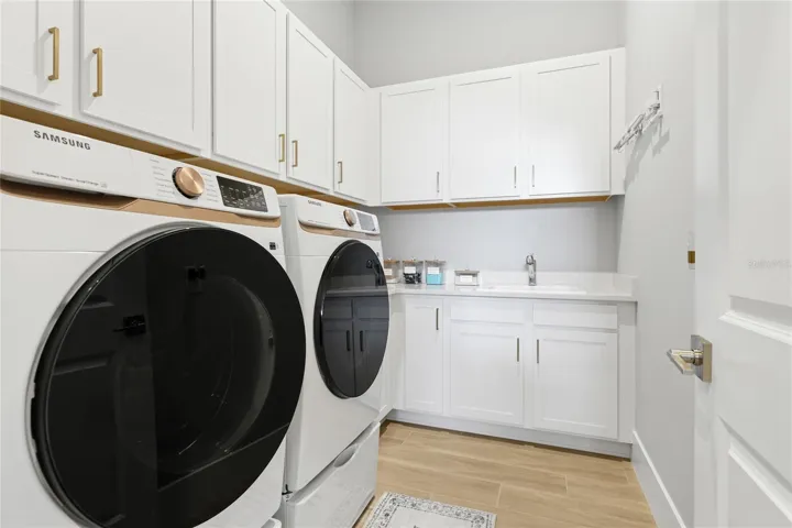 Dedicated laundry room with additional cabinetry and sink.