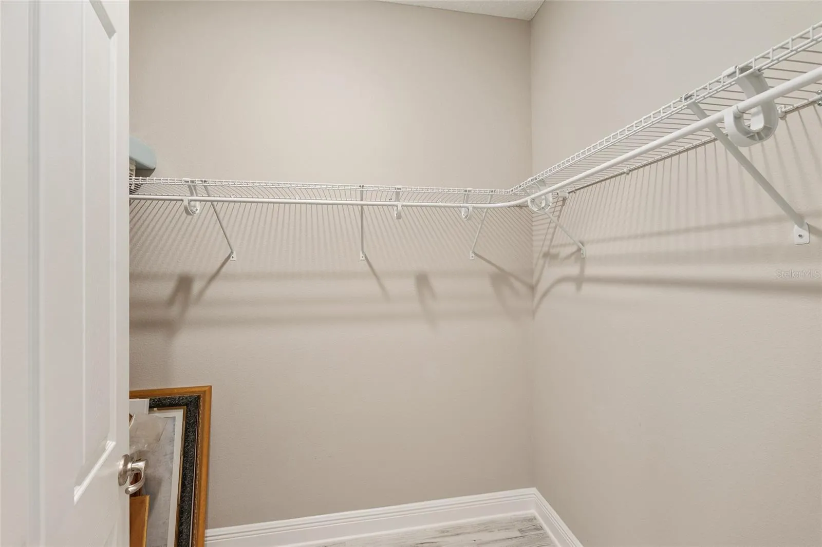 Second primary suite's spacious walk-in closet features wraparound shelving and ample hanging space, providing practical storage and organization.