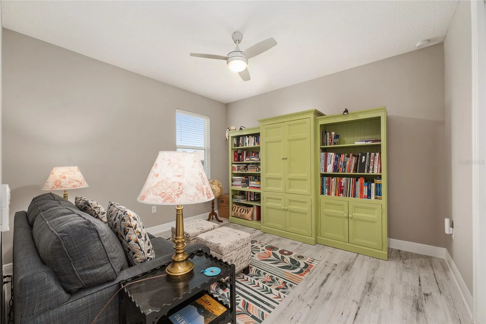 Comfortable third bedroom featuring ceramic plank flooring, ceiling fan with light, neutral finishes, and natural light.currently used as a den
