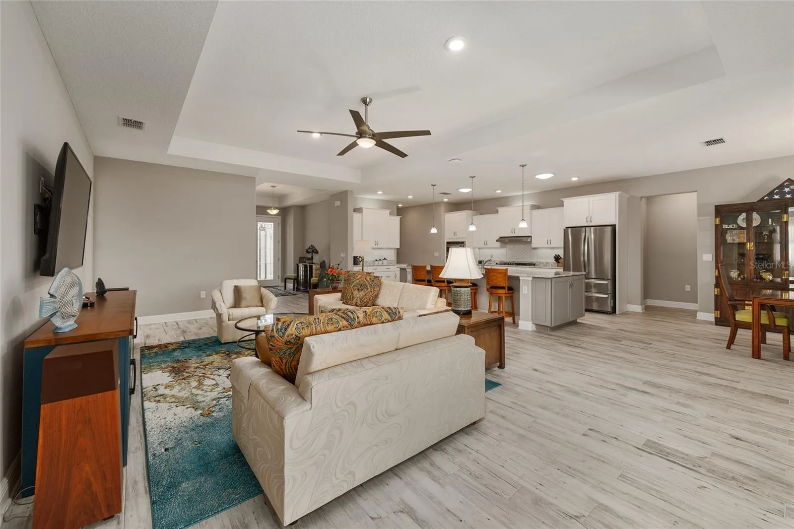 Designed for comfortable living and effortless entertaining, this spacious open floor plan showcases neutral finishes, ceramic plank flooring, elegant tray ceilings, upgraded hardware, dovetail drawers, and ceiling fans with integrated lighting, creating a warm and inviting atmosphere throughout.