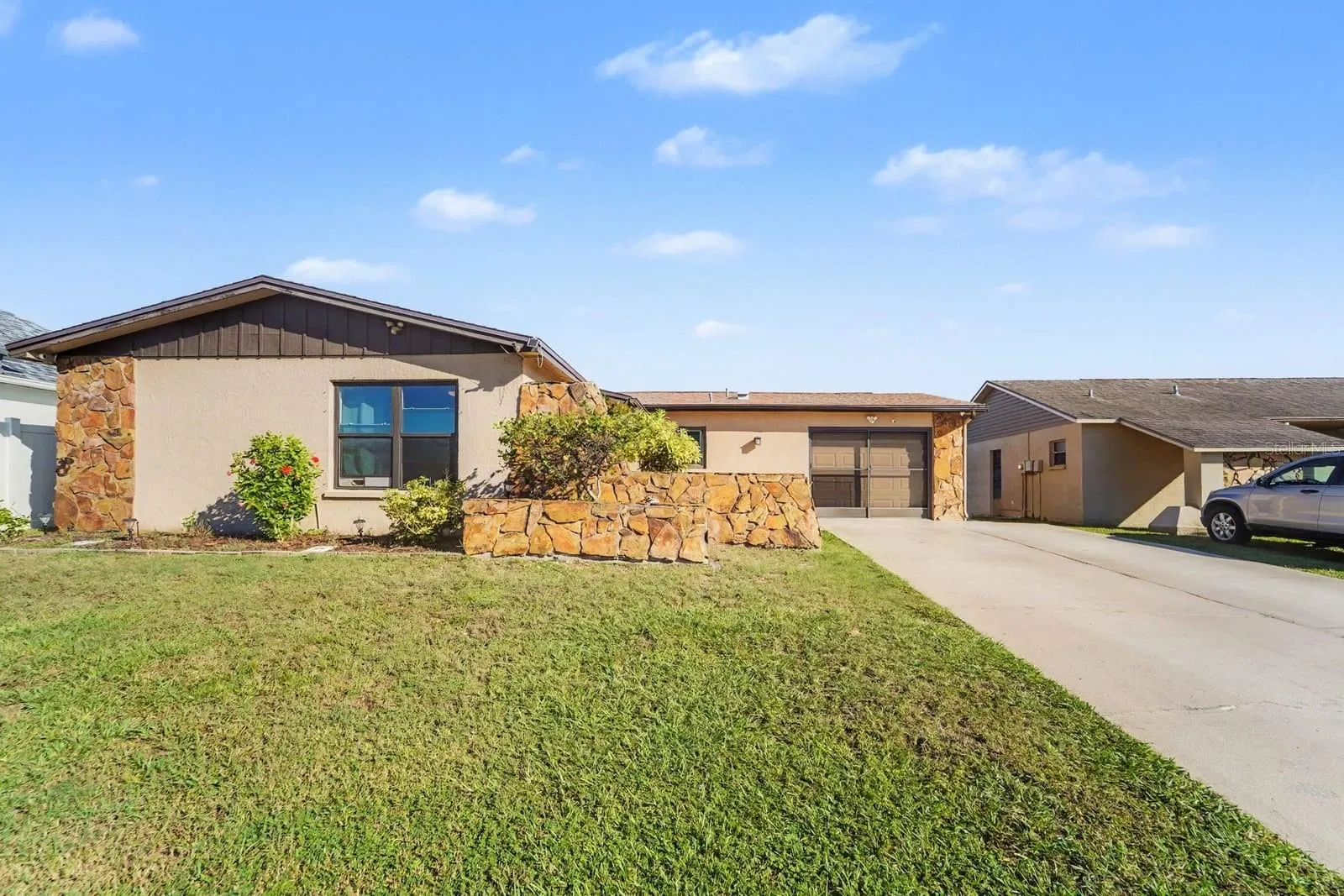 Stone & stucco contemporary home with manicured lawn and attached garage