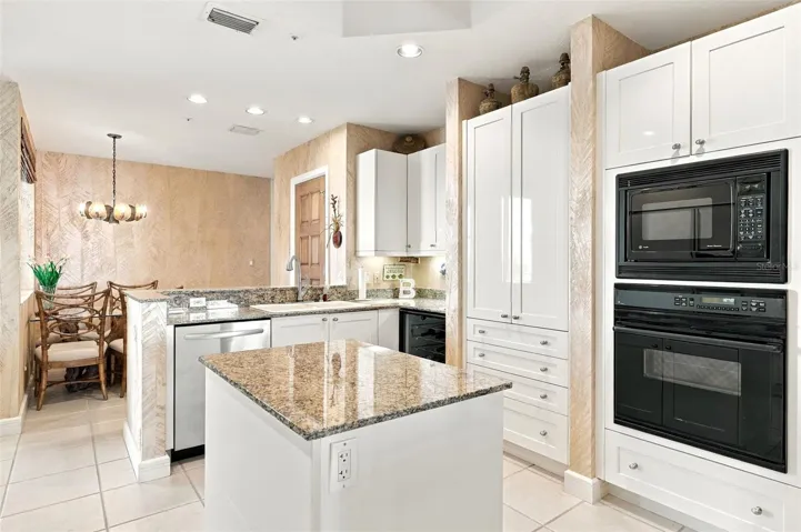 Thoughtfully designed kitchen with shaker style cabinetry, center island with cabinets and pull out drawers, planning desk, and wine refrigerator and closet pantry.