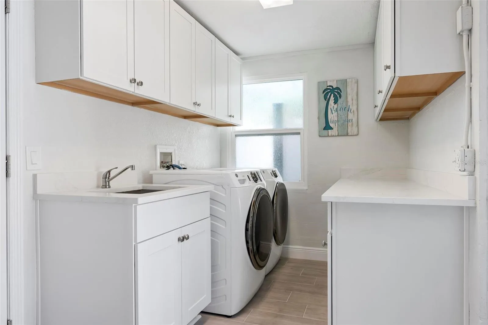 Indoor laundry room with utility sink and storage
