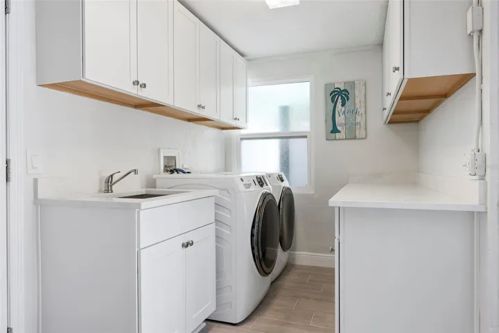 Indoor laundry room with utility sink and storage