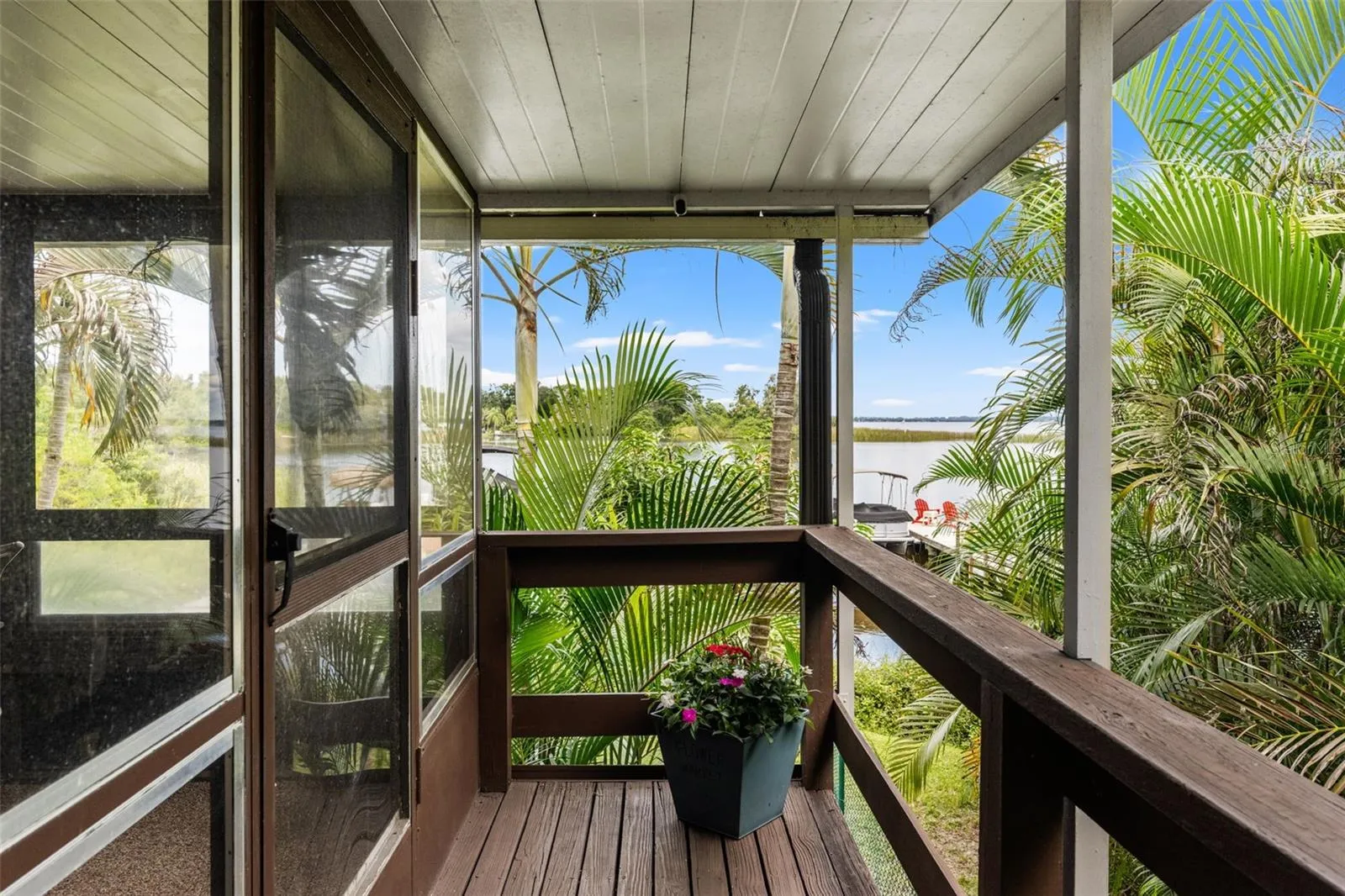 Your first glimpse of the waterfront! From the covered upper-level entry, enjoy views through the palms toward the water and private dock—a beautiful introduction to the Florida lifestyle waiting here.