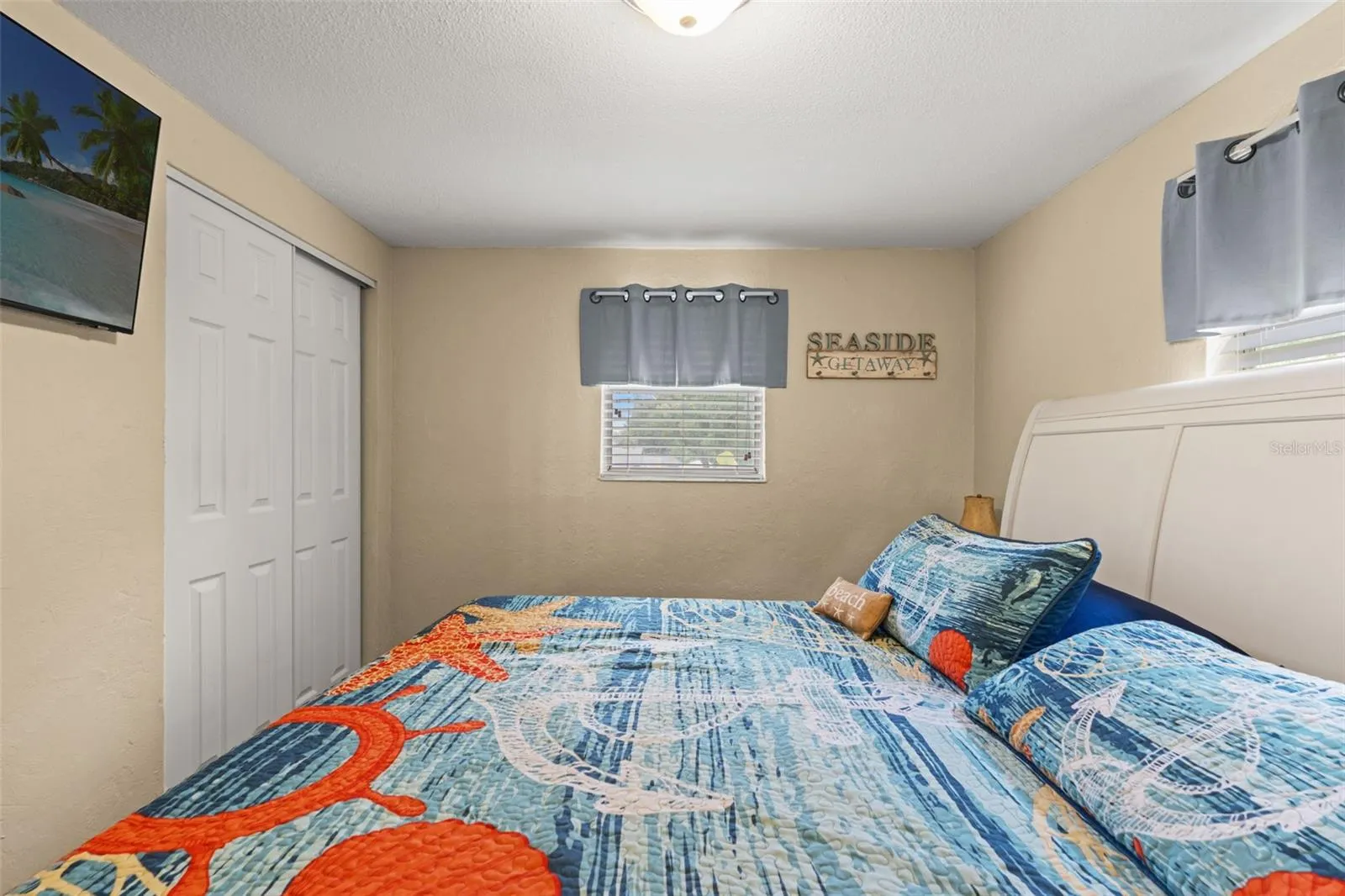 Another view of this inviting bedroom highlights the double-door closet, wood flooring, and natural light from two windows. A comfortable space for family or overnight guests.