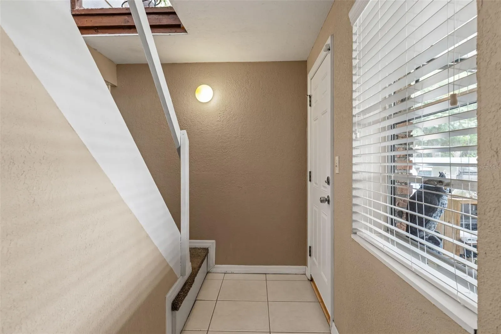 The lower level features its own exterior entrance, offering convenient access without passing through the upstairs living area. A tiled entryway, natural light, and interior stairway add to the functionality of this flexible layout.