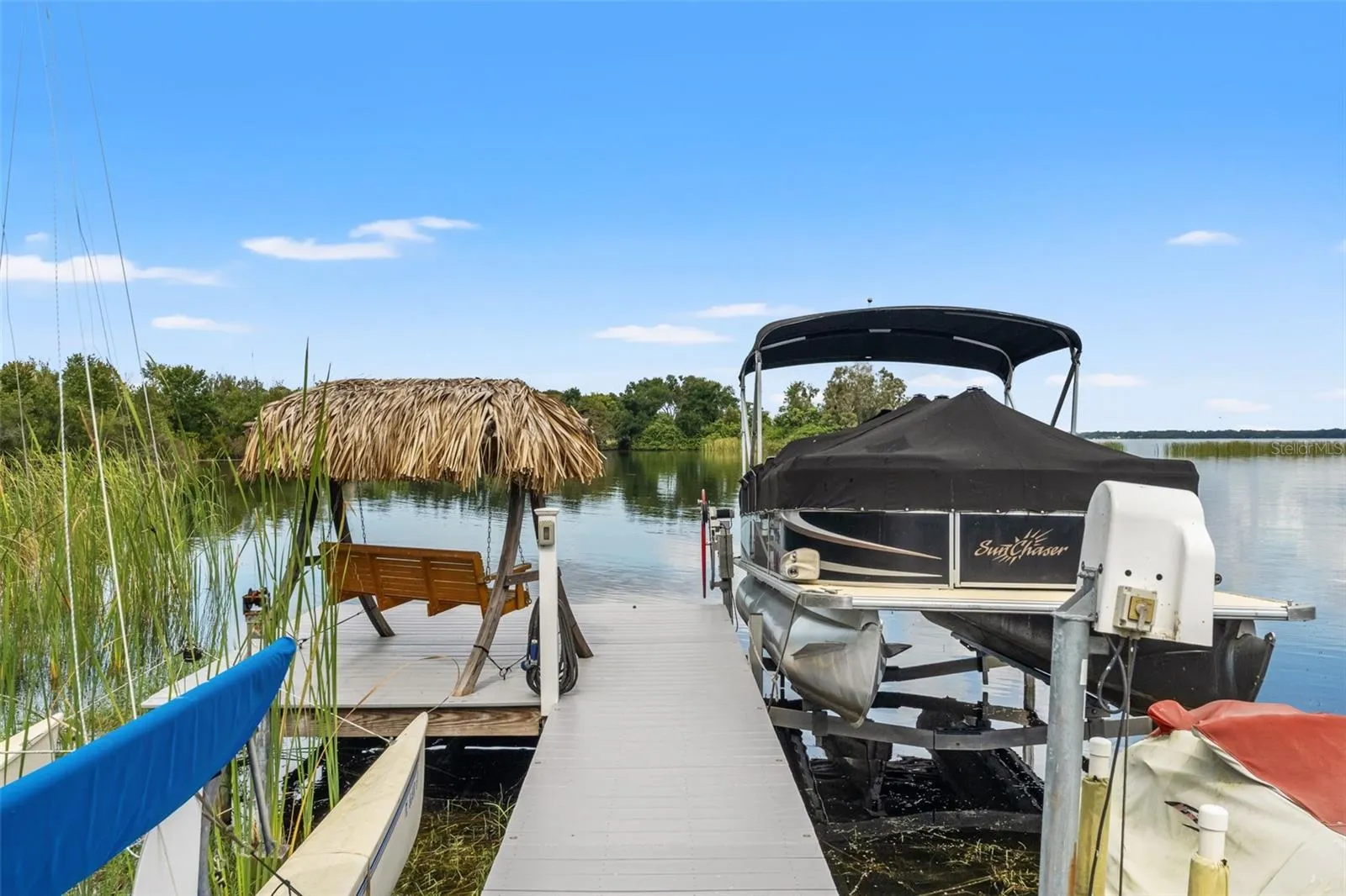The waterfront dock offers more than just a place for your boat. A charming thatched-roof swing creates a shaded retreat beside the pontoon boat lift, perfect for enjoying a morning coffee, watching wildlife, or relaxing after a day on the water.