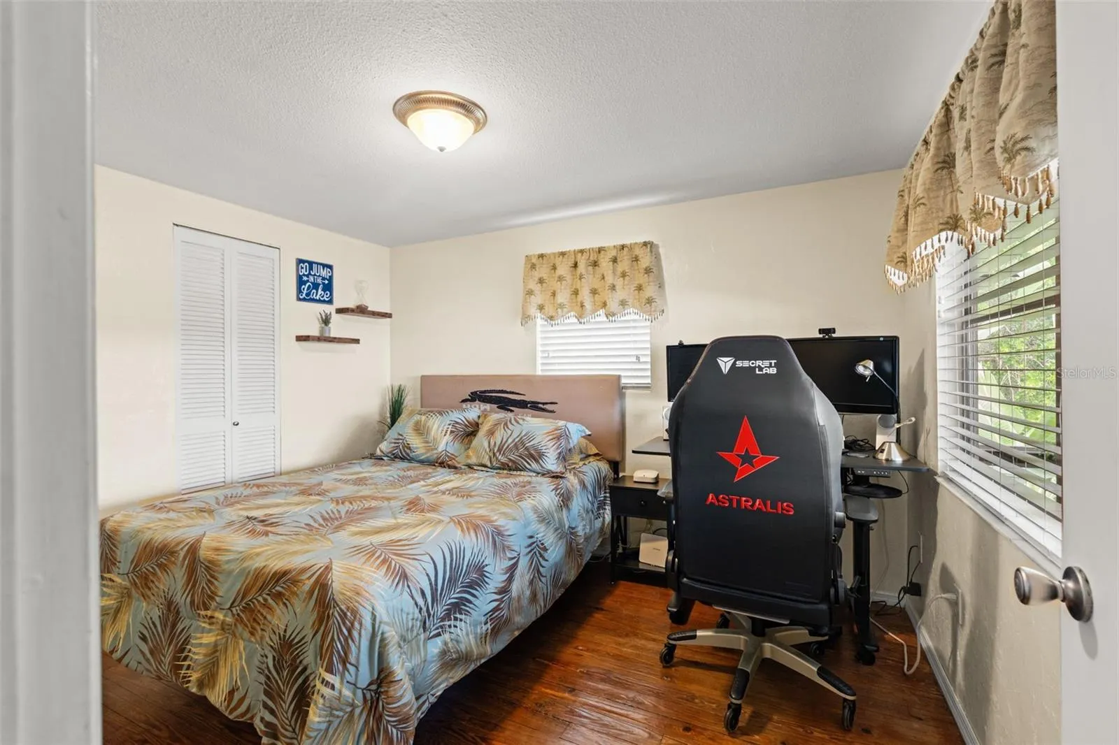 Warm wood floors and a dramatic stone fireplace anchor this comfortable living space. The open arrangement connects the living room with the dining area and kitchen, while sliding glass doors provide access to the screened porch.