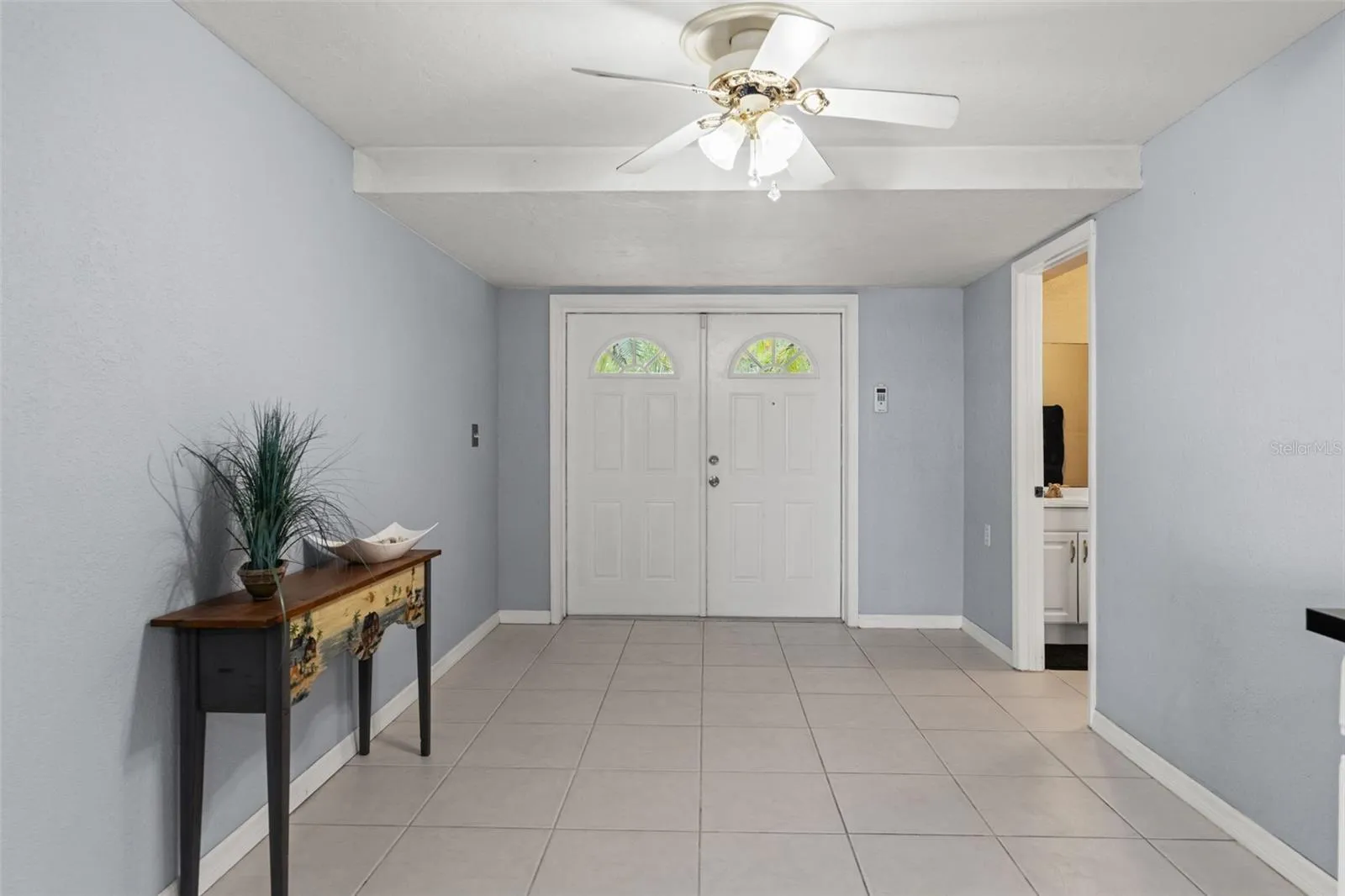 Double entry doors welcome you into the home's lower level, where neutral tile flooring, light-colored walls, and ceiling fans create a versatile space. With its own exterior entrance and nearby bathroom, this level offers flexibility for a variety of household needs.