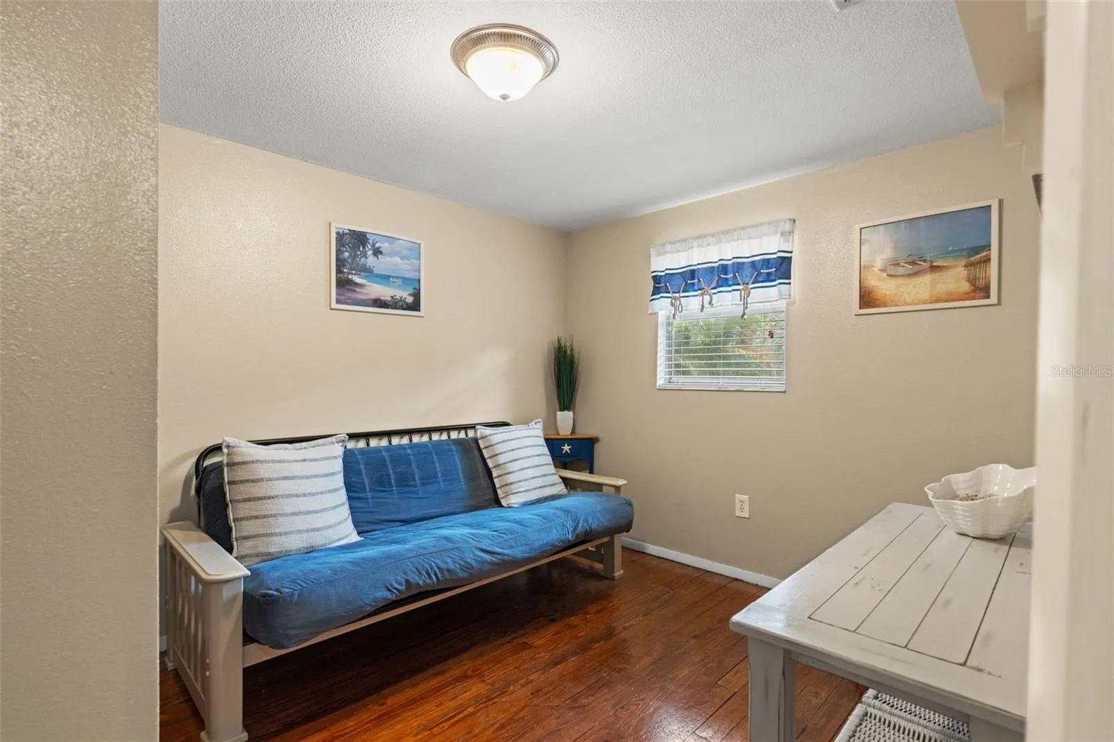 Need a home office, guest room, or quiet retreat? This versatile room features wood flooring, natural light, and space for a variety of furniture arrangements. Currently furnished with a futon, it offers flexibility to suit your needs.