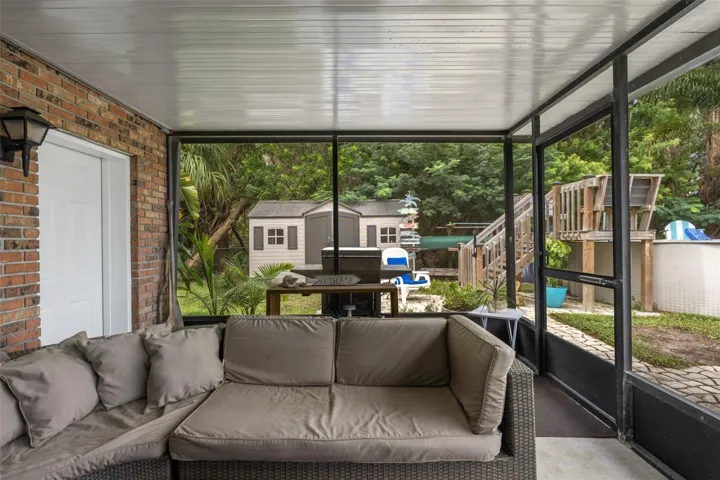 This covered, screened patio provides another comfortable outdoor gathering area, complete with sectional seating and access to the backyard. Beyond the enclosure, discover an above-ground pool, outdoor grilling area, and storage shed surrounded by mature trees.