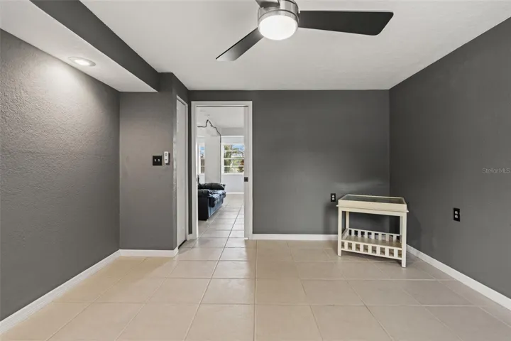 A second perspective highlights the room's open floor area, dark gray walls, and easy connection to the adjoining living space. The combination of natural light, closet storage, and separation from the main gathering area makes this a useful addition to the home's lower level.