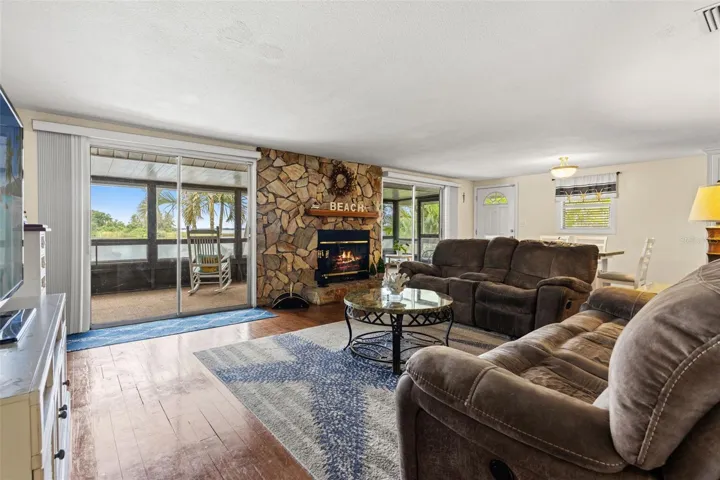 The spacious living room offers flexible furniture arrangements, wood flooring, and convenient access to the screened porch. Two nearby doorways connect to additional rooms, making the upper-level layout both practical and comfortable.