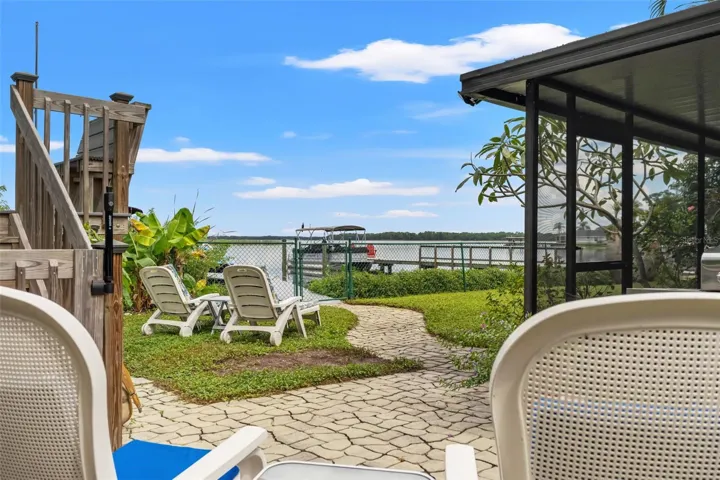 From your backyard patio, enjoy beautiful views across the water. A winding paver pathway leads past lounge chairs toward the fenced waterfront and dock, making it easy to move between relaxing in the yard and spending time on the water.