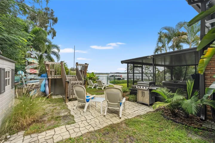 There's plenty of room to enjoy the Florida lifestyle! This backyard gathering area features a paver patio, grilling station, lounge seating, and an above-ground pool with a raised deck. Just beyond, the waterfront and dock create a beautiful backdrop for outdoor entertaining.
