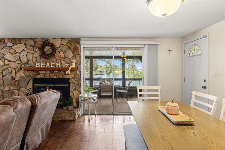 Imagine enjoying dinner with the water just beyond your windows! The dining area sits beside a striking stone fireplace, with sliding glass doors opening to a screened porch overlooking Lake Tarpon.