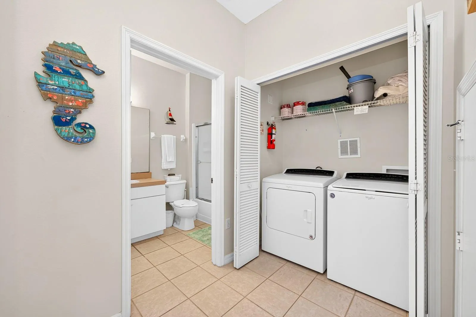A first-floor laundry closet is complete with washer, dryer and shelving for storage.