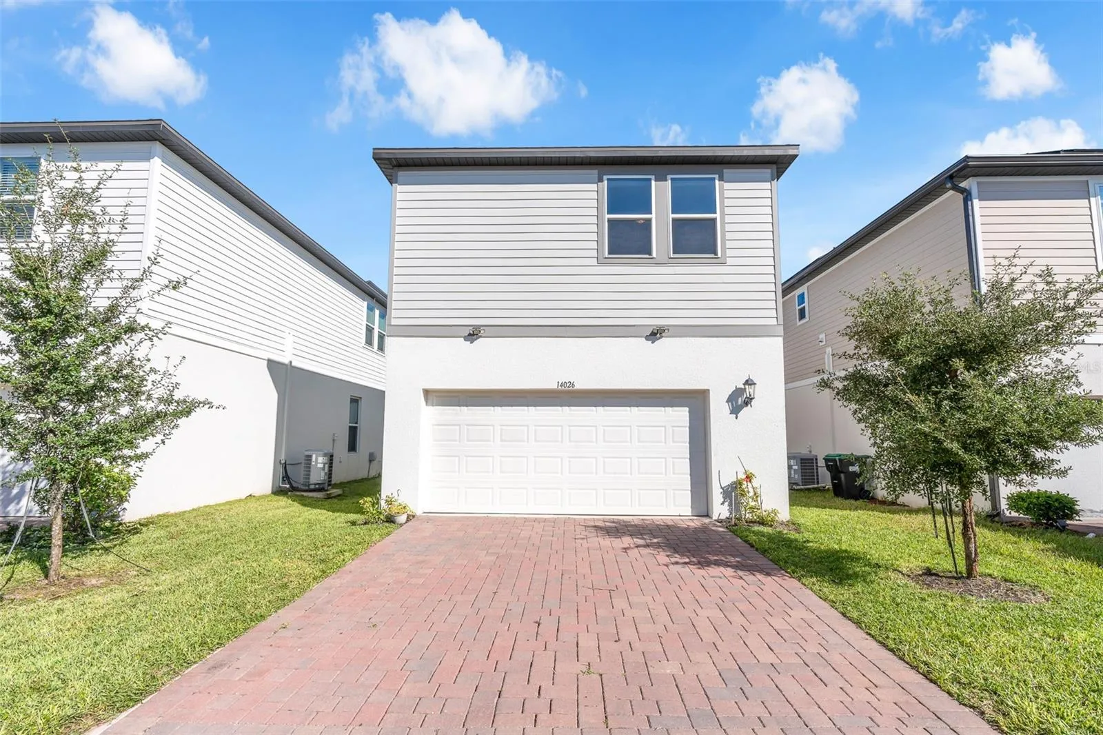 Rear exterior with two-car garage and paver driveway.