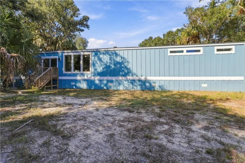 COUNTRY CHARM &amp; ROOM TO ROAM! Another exterior view showcases the home's spacious setting, attractive siding, rear steps &amp; surrounding greenery.