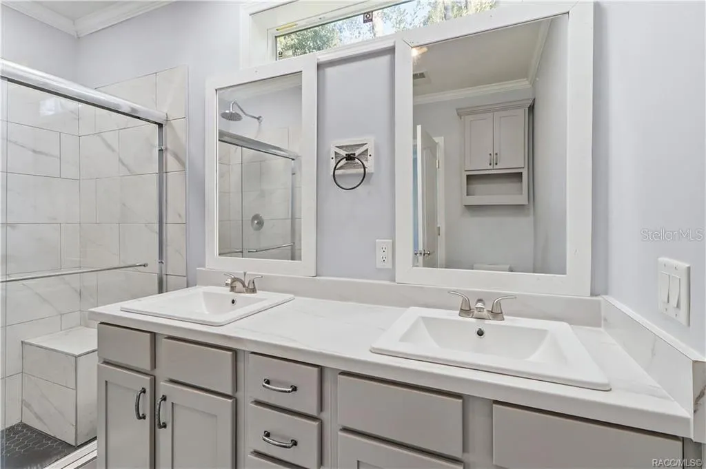 A BEAUTIFULLY FINISHED PRIMARY BATH! Enjoy a DOUBLE-SINK VANITY w/GRAY CABINETRY, marble-look countertops, framed mirrors &amp; a spacious WALK-IN SHOWER.