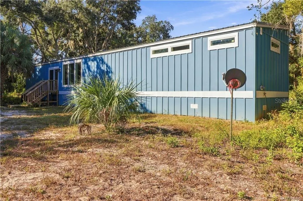 A LITTLE BIT COUNTRY, A LOT TO LOVE! The home's attractive BLUE EXTERIOR, WHITE TRIM &amp; METAL ROOF complement the surrounding natural Florida landscape.