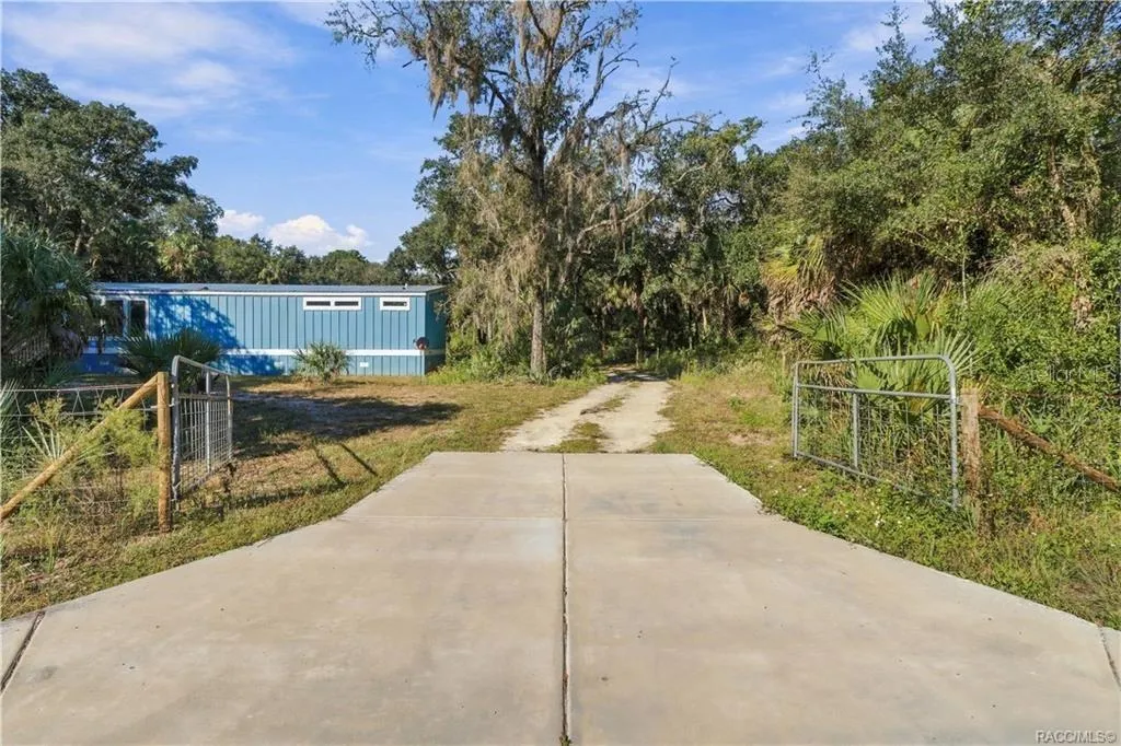 A GATED ENTRANCE WELCOMES YOU! The concrete driveway apron leads through a gated entrance into the 1.42 FULLY FENCED ACRES, offering space for vehicles &amp; outdoor toys.