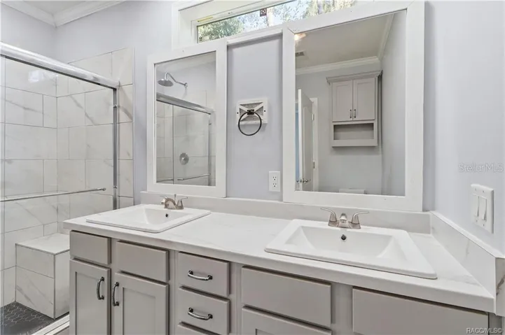 A BEAUTIFULLY FINISHED PRIMARY BATH! Enjoy a DOUBLE-SINK VANITY w/GRAY CABINETRY, marble-look countertops, framed mirrors &amp; a spacious WALK-IN SHOWER.