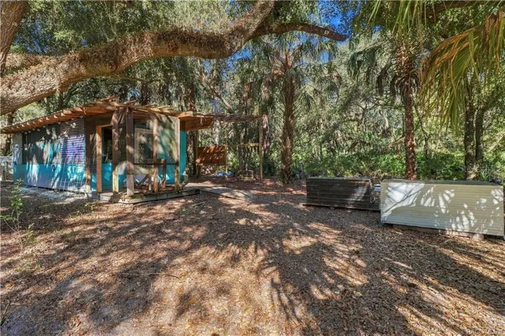 COUNTRY CHARACTER &amp; OUTDOOR POSSIBILITIES! This rustic outbuilding features a covered wooden porch &amp; adjoining open-air structure beneath the shade of mature trees.