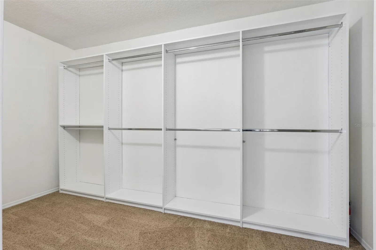 Primary suite walk-in closet featuring custom-built-in organization system