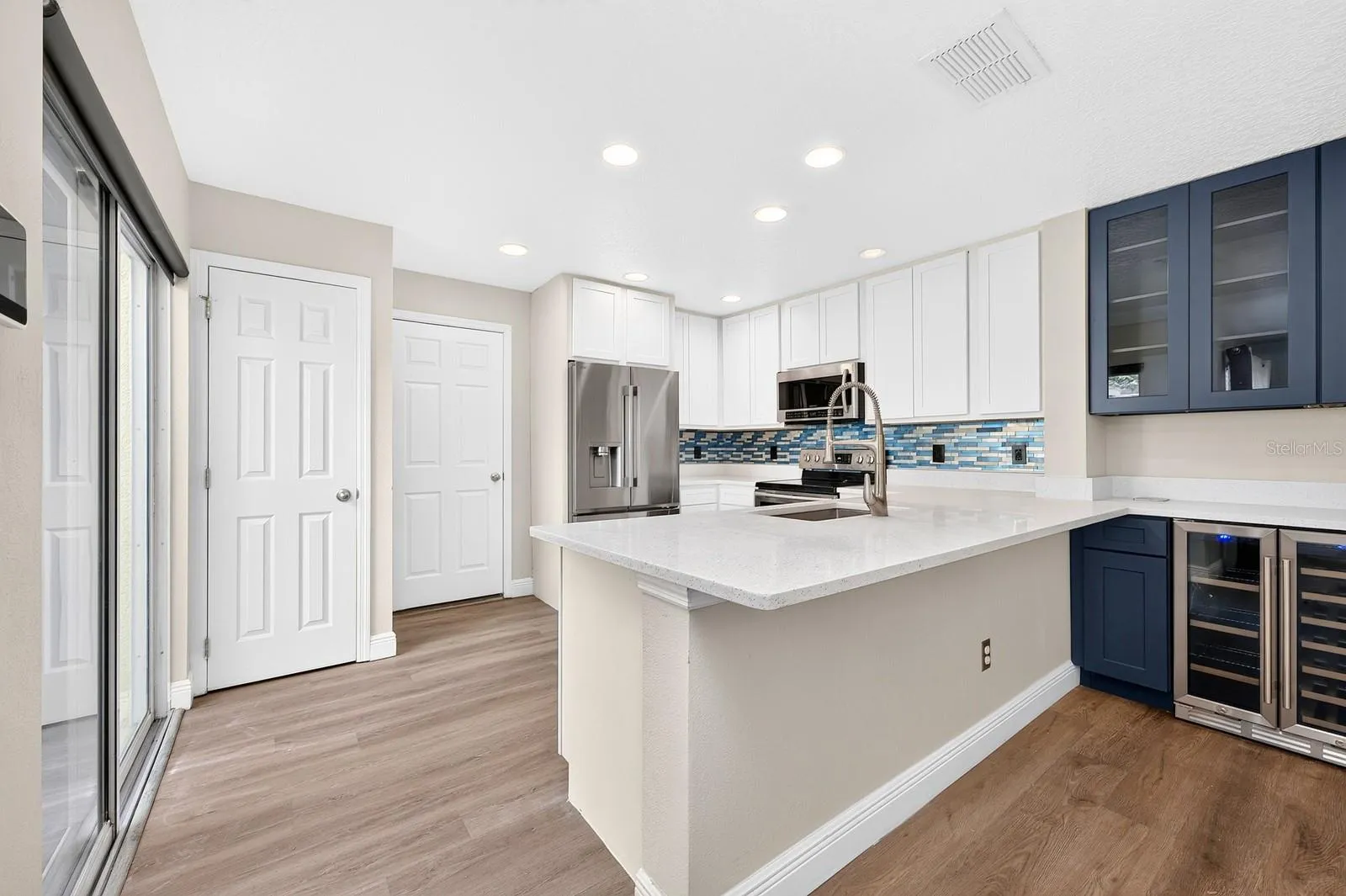 The Kitchen's modern cabinets and sparkling quartz counters blend seamlessly into the custom matching beverage bar--perfect for entertaining!