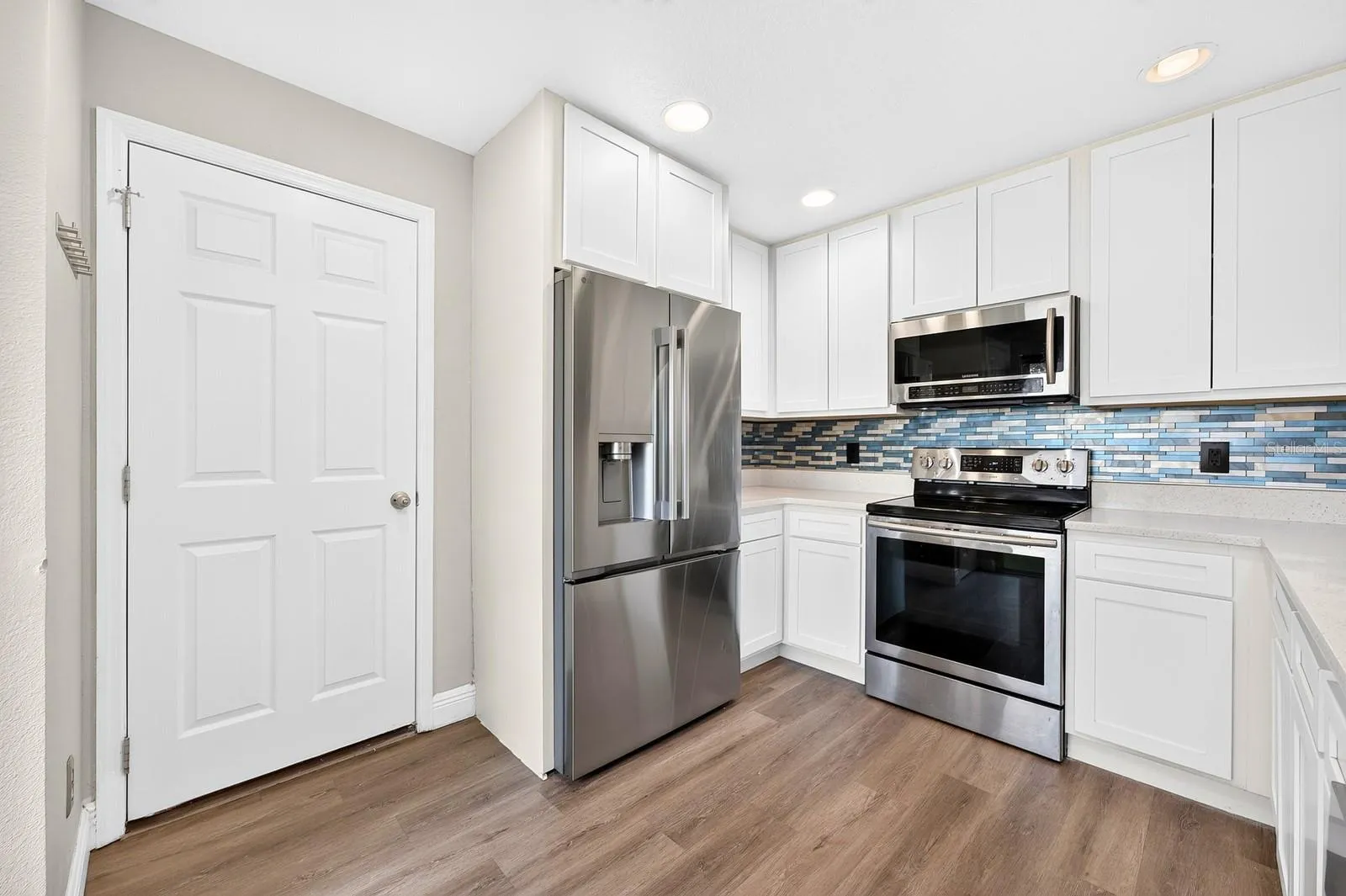 RECESSED LIGHTING brightens the space, while the NEW STAINLESS STEEL REFRIGERATOR (2025) and NEW BACKSPLASH (2025) complete the polished look.