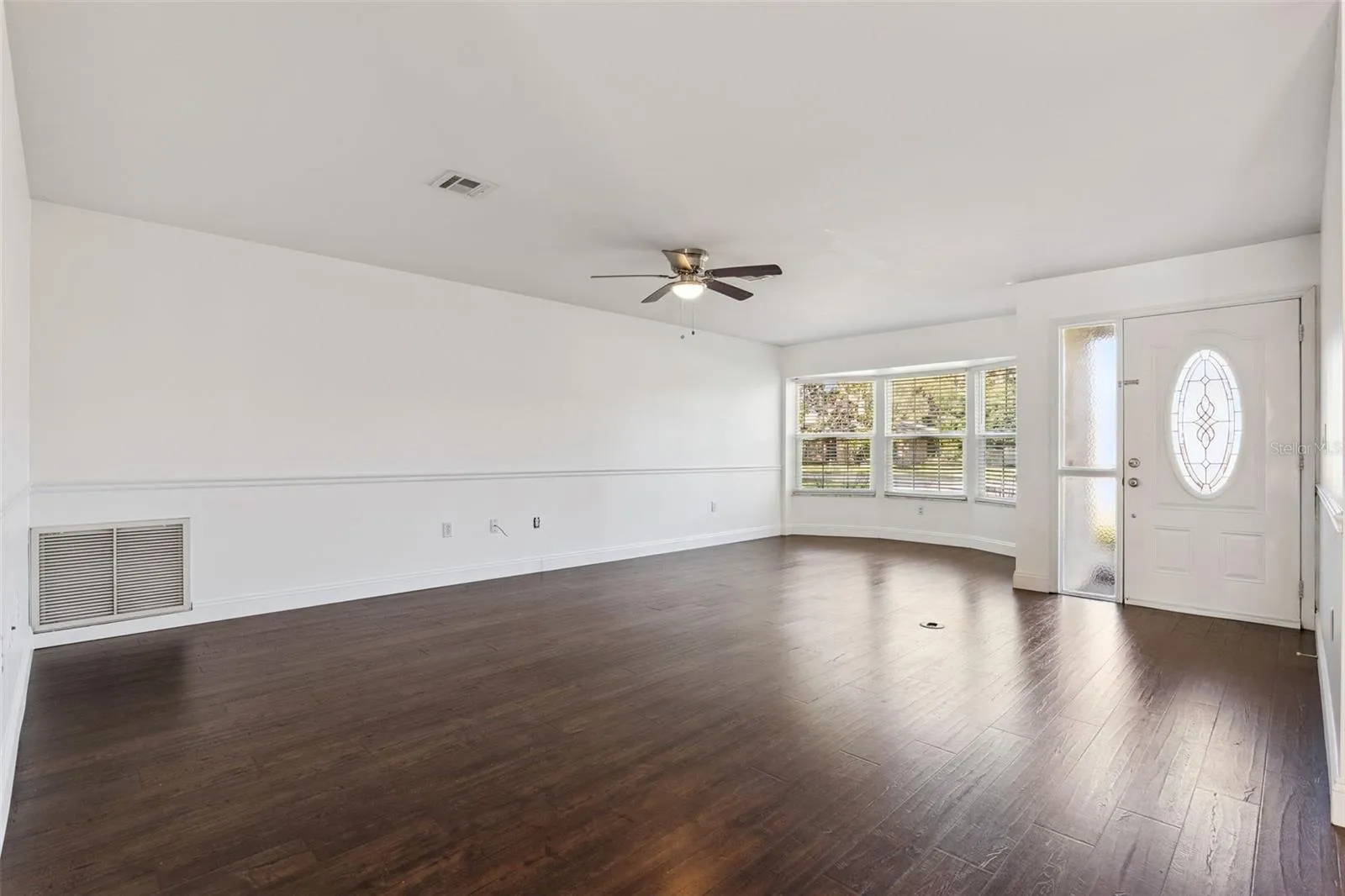 A bright living room with a bay window and rich wood-look floors