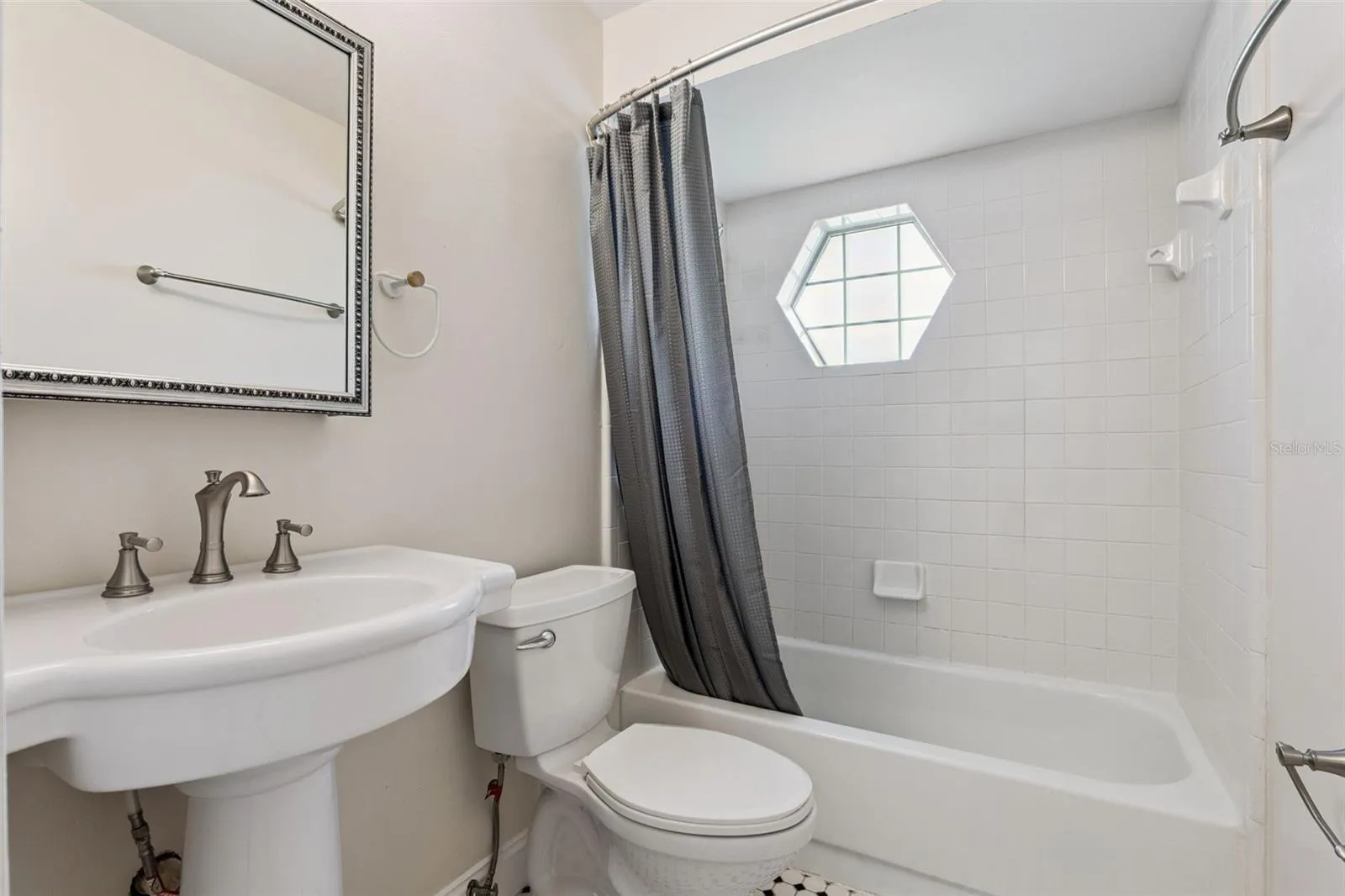 Guest bath with a tub/shower combo and a charming hexagon window