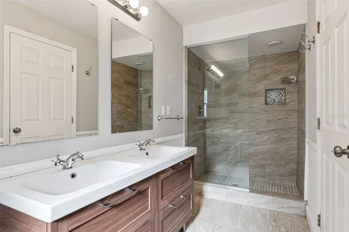 Tiled walk-in shower with a glass panel and dual sinks