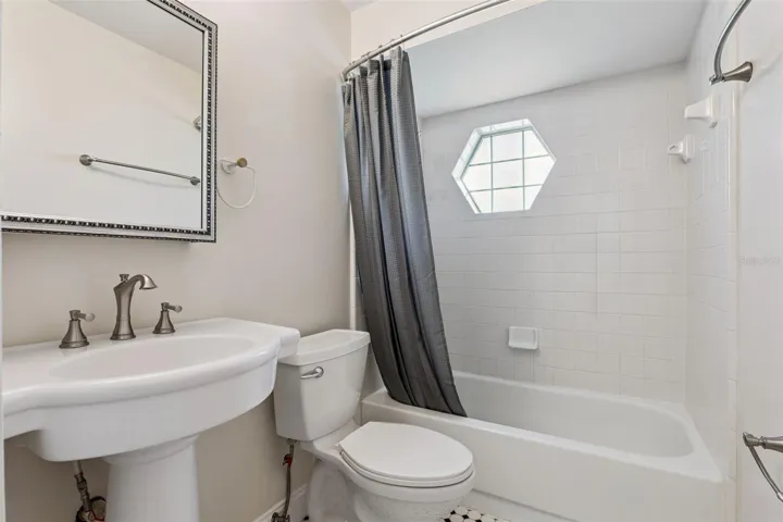 Guest bath with a tub/shower combo and a charming hexagon window