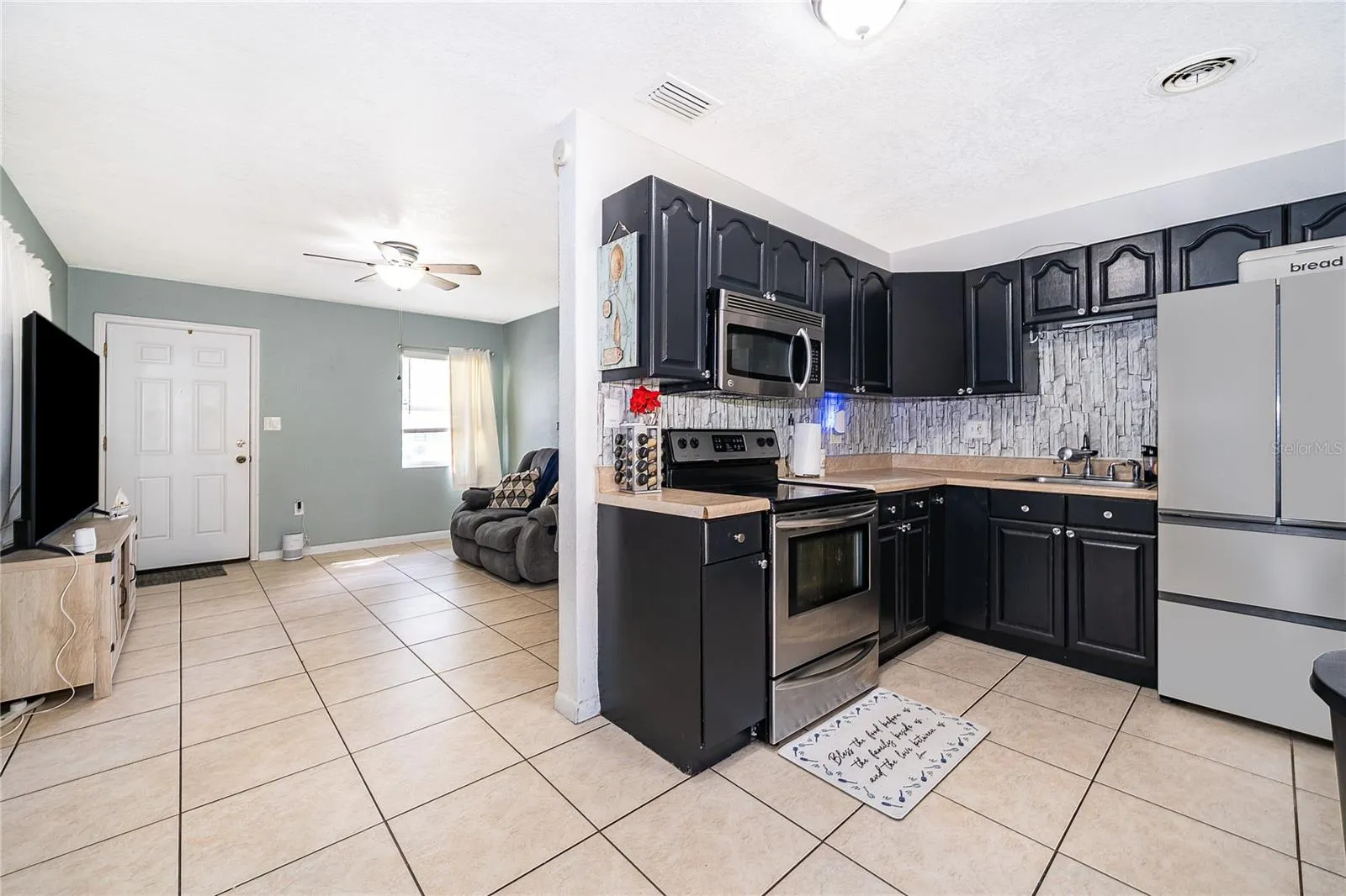 Enjoy preparing meals in this functional kitchen featuring dark cabinetry, ample countertop space, and easy access to the dining area.