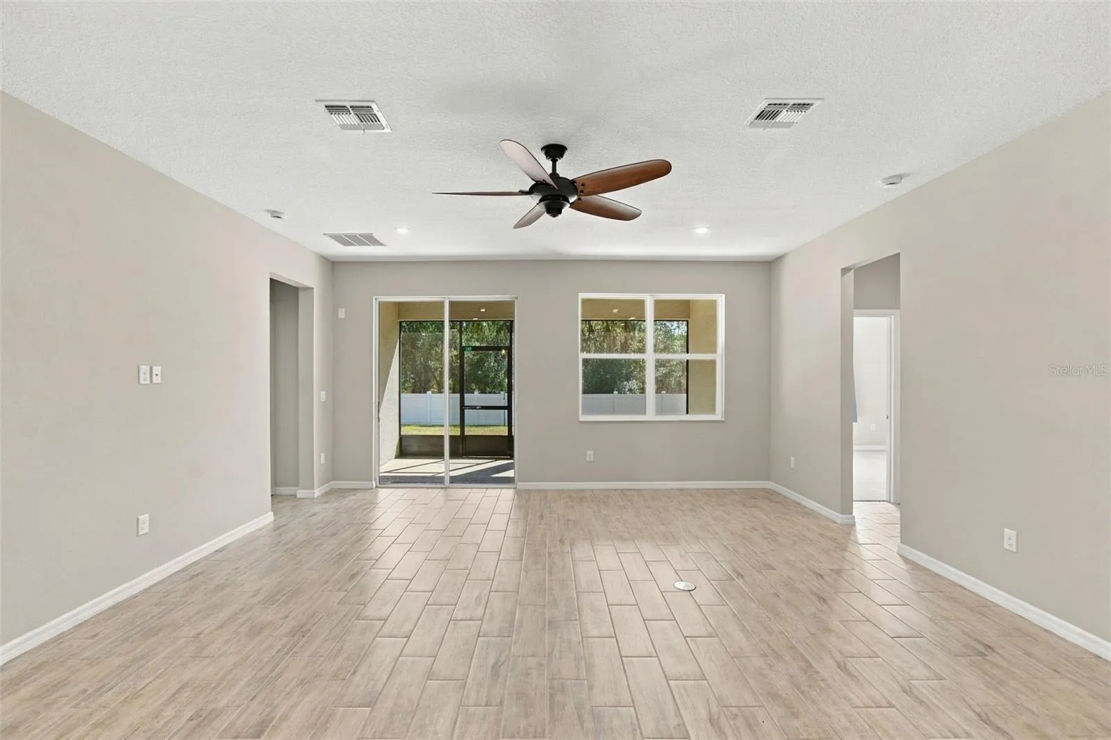 Living Room - to the left: entrance to primary suite,  to the right: hall leading to two additional bedrooms and full bath - screened in patio in background