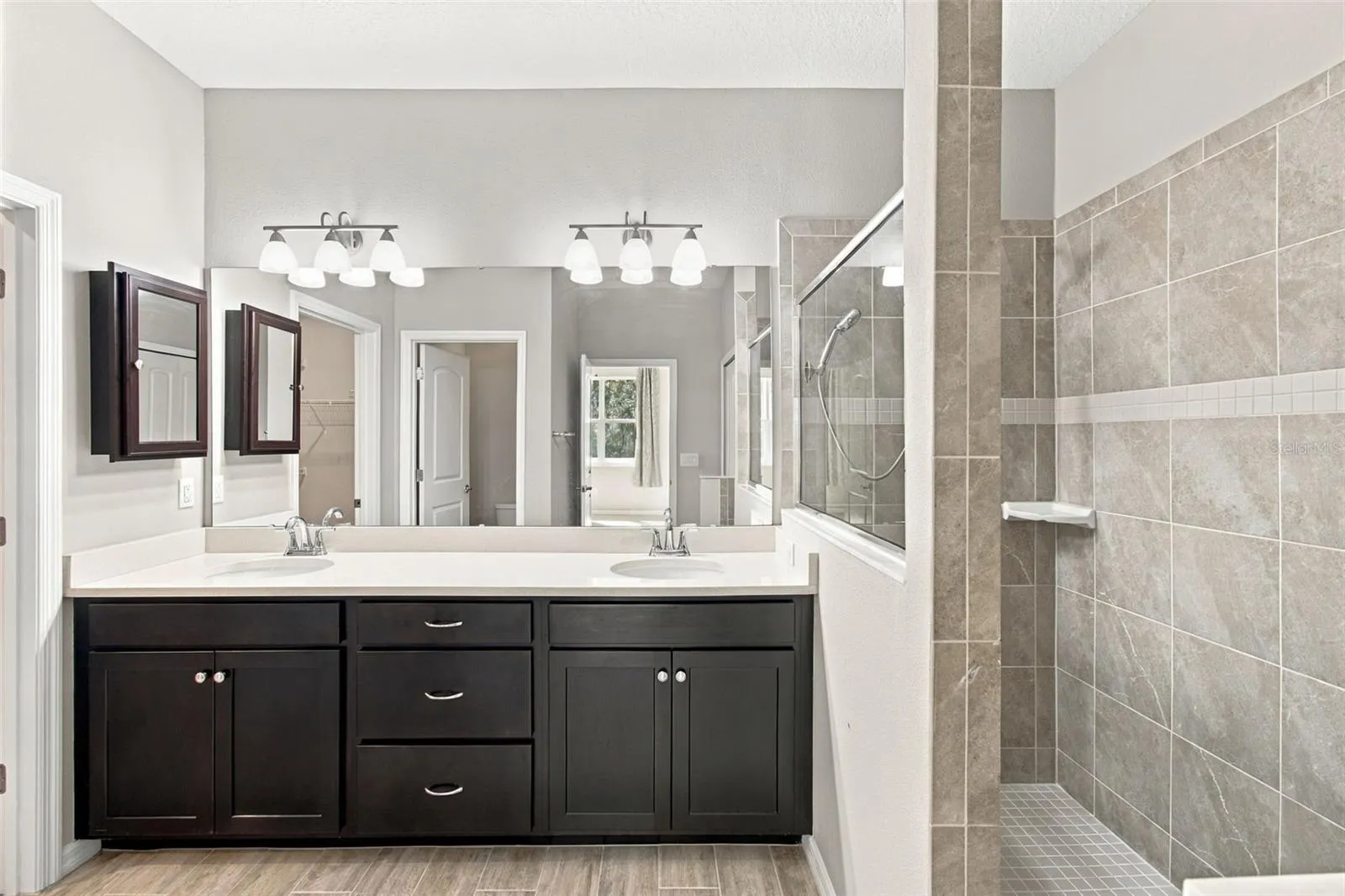 Double sink large vanity with quartz counters and tiled walk-in shower