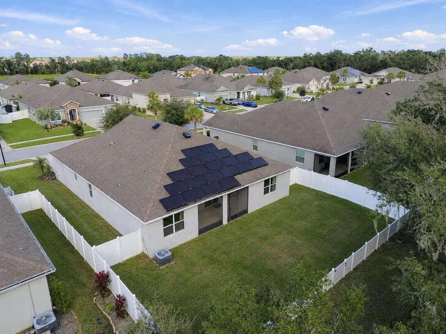 Overview of backyard and rear exterior of home by drone - solar panels and solar ventilation on roof