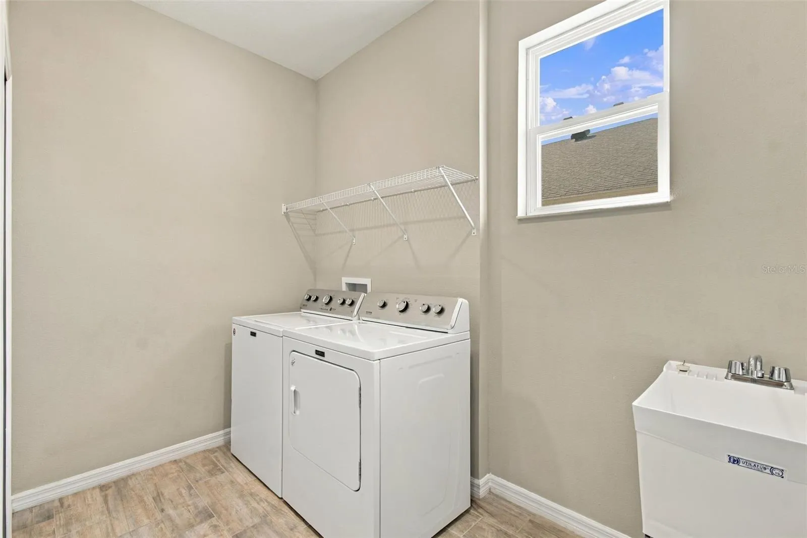 Large Laundry Room with deep utility sink and window for natural light- large supply closet to the left (not pictured).