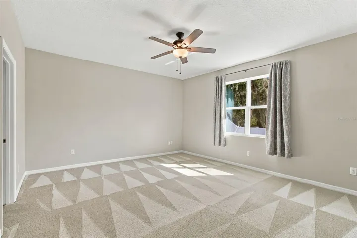 Primary Suite with ceiling fan and view of backyard oasis
