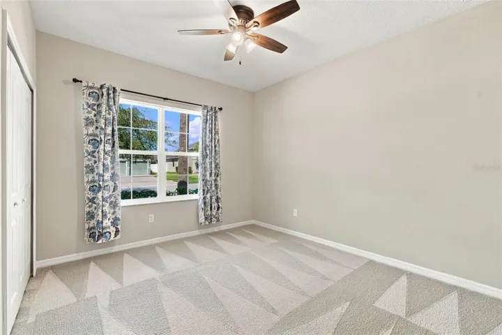 Guest bedroom with ceiling fan &amp; large window facing the front yard