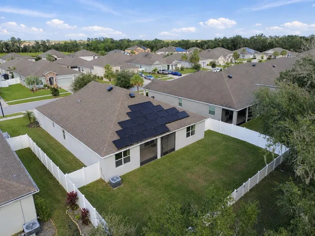 Overview of backyard and rear exterior of home by drone - solar panels and solar ventilation on roof