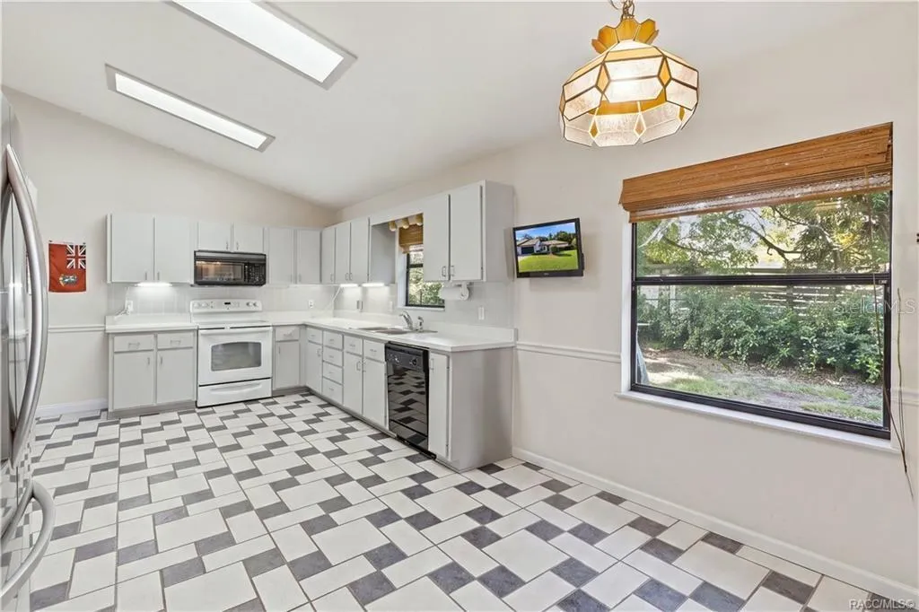 LET'S GET COOKING! Bright, spacious EAT-IN KITCHEN features WHITE CABINETRY, ample counter space, TILE FLOORING &amp; a VAULTED CEILING!