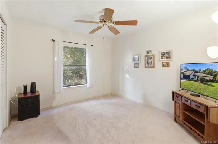 Additional view of the guest bedroom showcasing natural light, ceiling fan, carpeting.