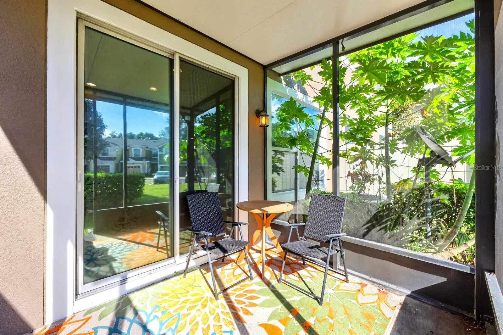 Sliding glass doors extend the living space outdoors to a COVERED, SCREENED REAR PORCH overlooking a peaceful green space.